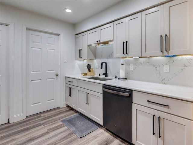 kitchen featuring stainless steel dishwasher, a sink, decorative backsplash, light wood-style flooring, and recessed lighting