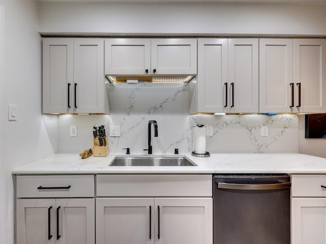 kitchen with stainless steel dishwasher, a sink, decorative backsplash, and light stone countertops
