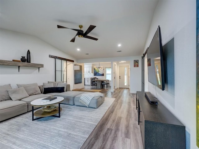 living room with a barn door, lofted ceiling, light wood-style floors, ceiling fan, and recessed lighting