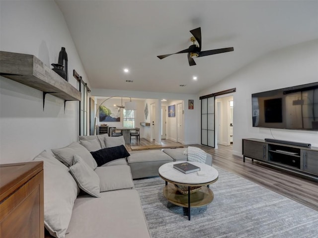 living room featuring a barn door, vaulted ceiling, ceiling fan, wood finished floors, and recessed lighting