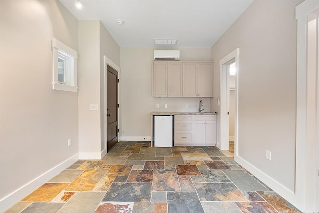 5517 Woodview Ave, Austin, TX 78756 - kitchen featuring visible vents, stone tile flooring, baseboards, an AC wall unit, and light countertops