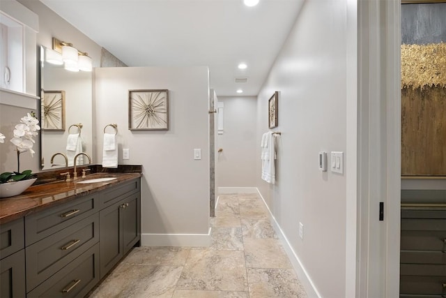 5517 Woodview Ave, Austin, TX 78756 - bathroom with double vanity, stone finish flooring, a sink, baseboards, and recessed lighting