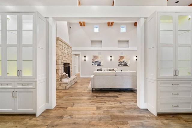 5517 Woodview Ave, Austin, TX 78756 - living room with a stone fireplace, light wood-type flooring, beam ceiling, high vaulted ceiling, and baseboards