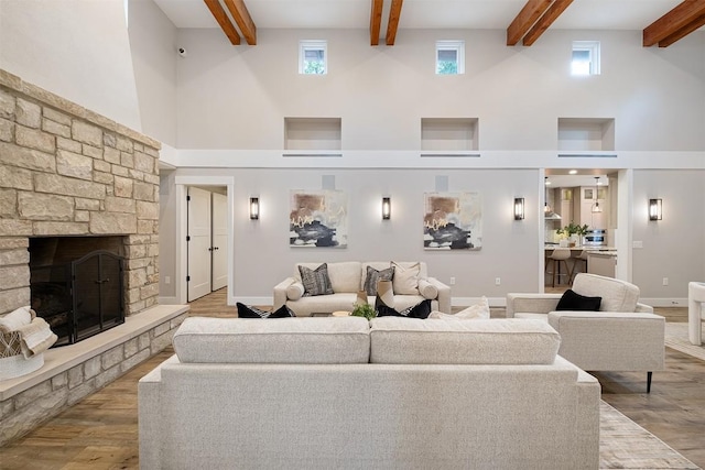 5517 Woodview Ave, Austin, TX 78756 - living area with beamed ceiling, a stone fireplace, wood finished floors, and a towering ceiling