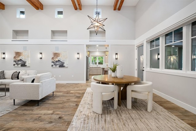 5517 Woodview Ave, Austin, TX 78756 - dining area featuring light wood-type flooring, baseboards, a towering ceiling, and beam ceiling