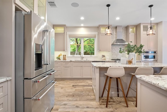 5517 Woodview Ave, Austin, TX 78756 - kitchen with visible vents, a breakfast bar, wall chimney range hood, a sink, and appliances with stainless steel finishes