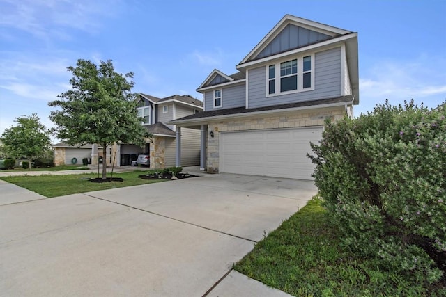 craftsman-style house with board and batten siding, a front lawn, concrete driveway, an attached garage, and stone siding