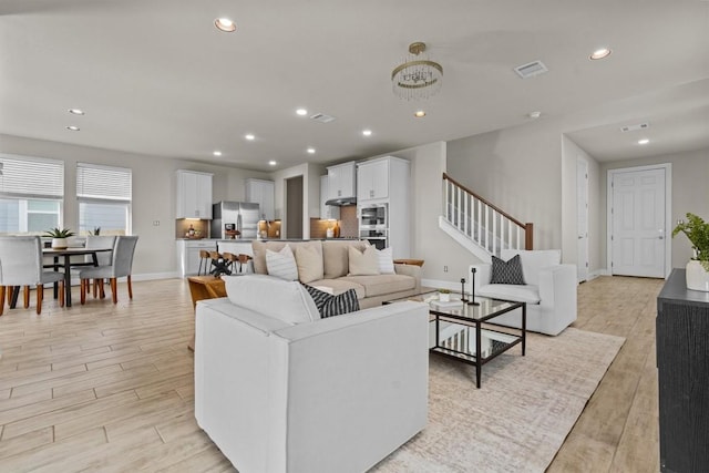 living area featuring visible vents, light wood-style flooring, stairs, and recessed lighting