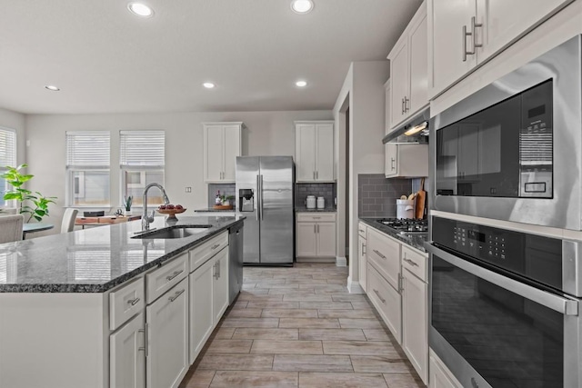 kitchen featuring appliances with stainless steel finishes, tasteful backsplash, a sink, white cabinets, and recessed lighting