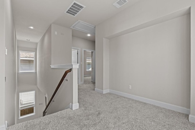hallway with attic access, carpet flooring, an upstairs landing, and visible vents