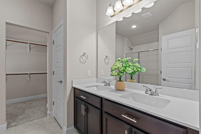 bathroom featuring double vanity, a spacious closet, a shower stall, and a sink