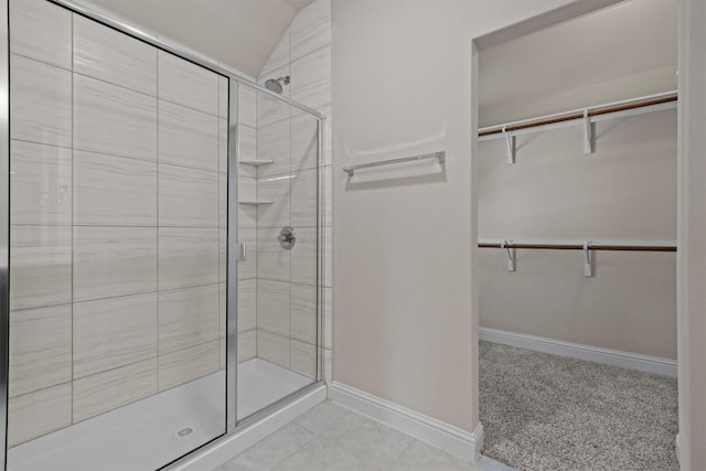 full bathroom with baseboards, a walk in closet, and a shower stall