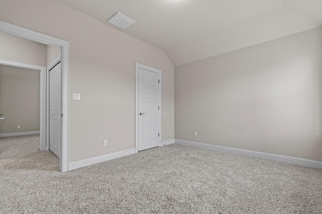 unfurnished bedroom featuring visible vents, carpet, baseboards, and vaulted ceiling