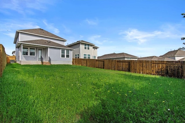 back of house with a fenced backyard and a yard
