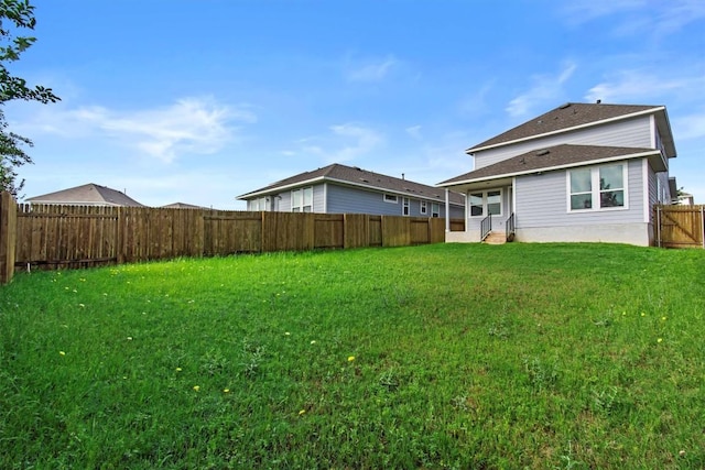 rear view of property featuring entry steps, a yard, and a fenced backyard