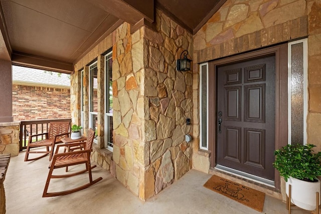 entrance to property featuring covered porch and stone siding