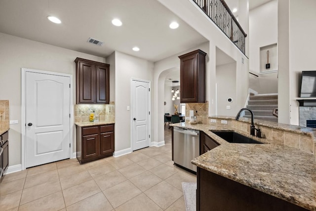 kitchen with decorative backsplash, visible vents, arched walkways, dishwasher, and a sink