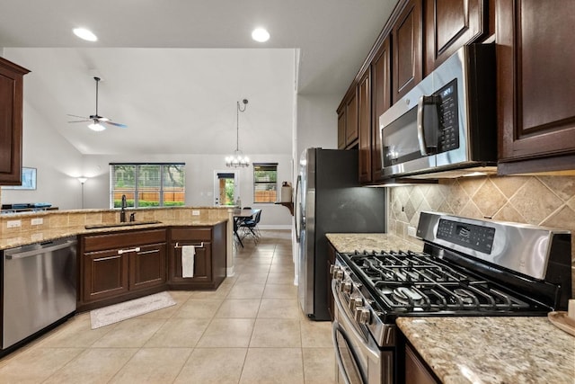 kitchen with appliances with stainless steel finishes, tasteful backsplash, a sink, ceiling fan with notable chandelier, and lofted ceiling