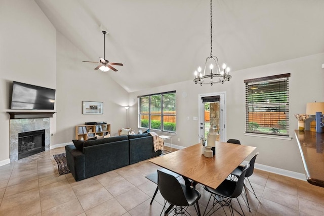 dining area with light tile patterned flooring, baseboards, high vaulted ceiling, a tile fireplace, and ceiling fan with notable chandelier
