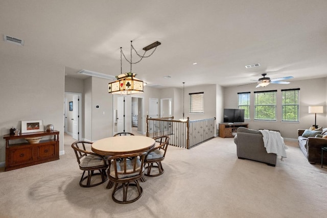 dining space featuring a ceiling fan, visible vents, and light carpet