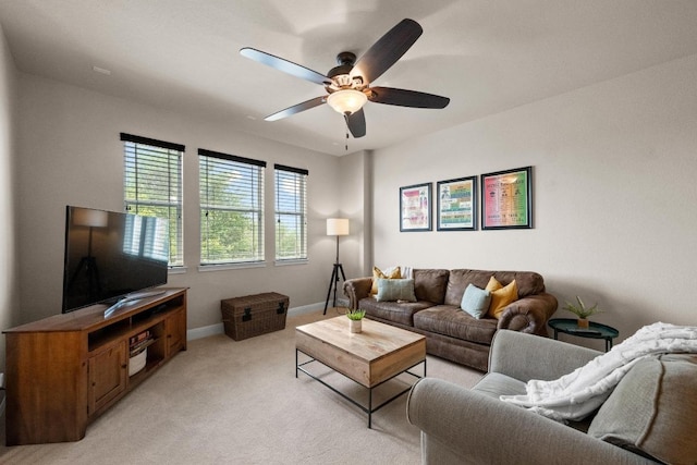 living area with baseboards, a ceiling fan, and light colored carpet