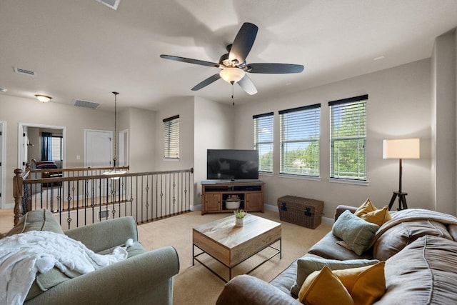 living area featuring ceiling fan, light colored carpet, baseboards, and visible vents