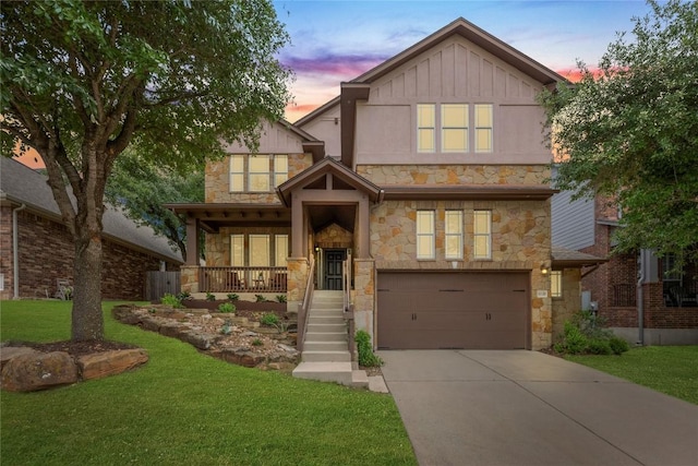 view of front of property featuring a garage, a yard, stone siding, and concrete driveway