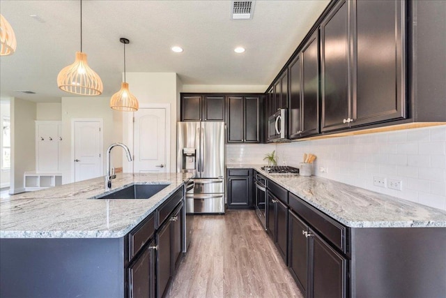 kitchen featuring visible vents, a sink, light stone countertops, and stainless steel appliances