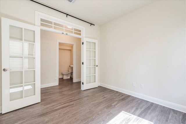 unfurnished bedroom with baseboards, french doors, and wood finished floors