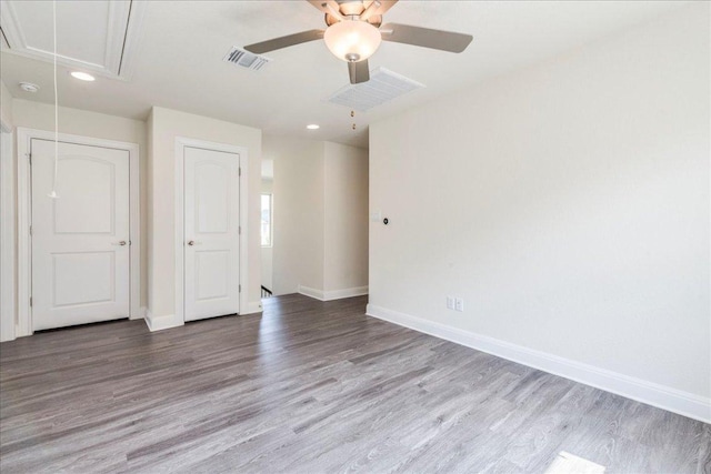 empty room featuring attic access, recessed lighting, baseboards, wood finished floors, and visible vents