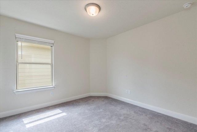 carpeted empty room featuring baseboards