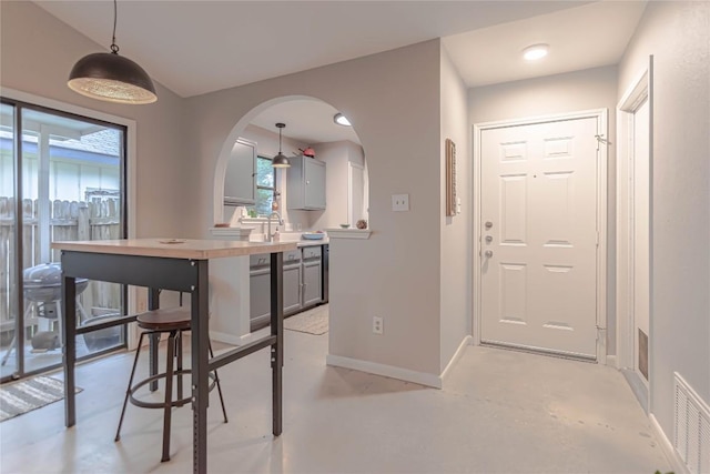 dining area featuring baseboards, arched walkways, finished concrete flooring, and visible vents