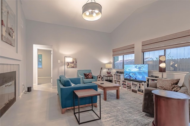 living room featuring a tiled fireplace, baseboards, and lofted ceiling