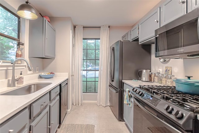 kitchen with a sink, light countertops, stainless steel appliances, light floors, and gray cabinetry