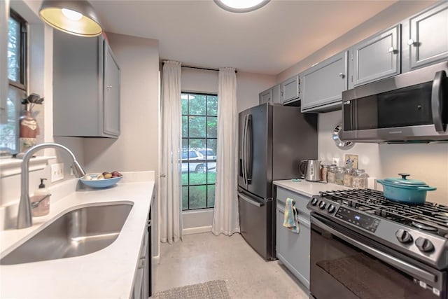 kitchen featuring a sink, light countertops, gray cabinetry, and stainless steel appliances