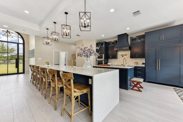 kitchen featuring an inviting chandelier, visible vents, built in fridge, a spacious island, and custom exhaust hood