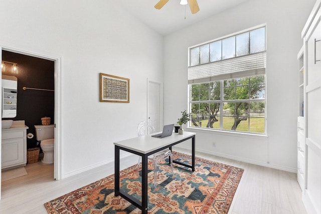 office space with light wood-style floors, baseboards, and a ceiling fan