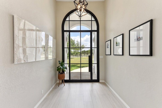 doorway with baseboards, a textured wall, and wood finished floors