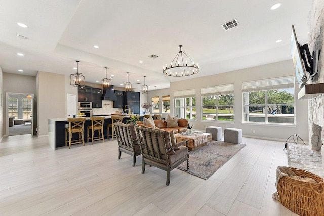 living area with recessed lighting, visible vents, an inviting chandelier, and light wood finished floors