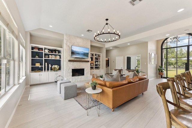 living area featuring a stone fireplace, visible vents, built in shelves, baseboards, and recessed lighting