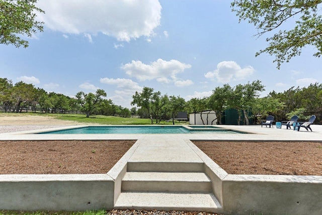 view of swimming pool with a storage unit, an outbuilding, a pool with connected hot tub, and a patio area