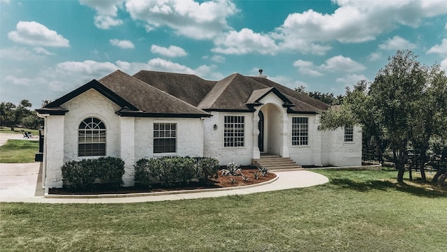 507 Saddletree Ln, Dripping Springs, TX 78620 - french country style house with a front yard, stone siding, and a shingled roof