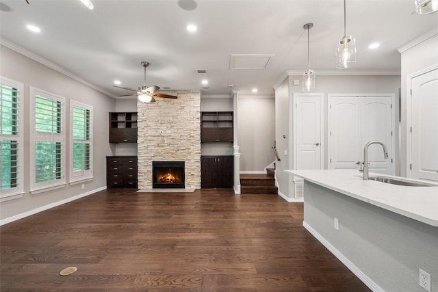unfurnished living room with a sink, ornamental molding, and a ceiling fan