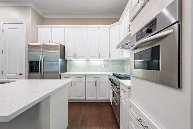 kitchen with under cabinet range hood, white cabinets, appliances with stainless steel finishes, and ornamental molding