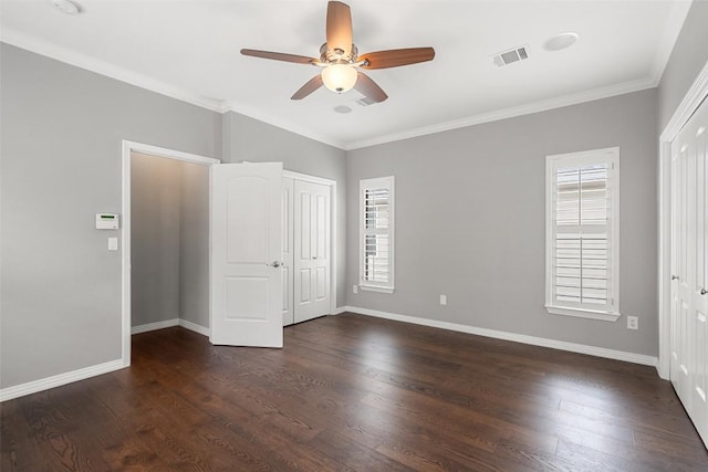unfurnished bedroom featuring dark wood-style flooring, baseboards, visible vents, and ornamental molding