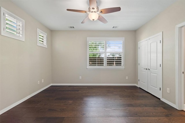 unfurnished bedroom with multiple windows, dark wood-type flooring, and visible vents