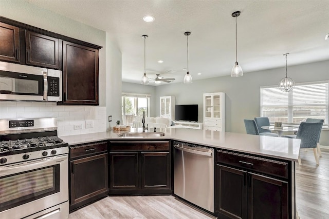 kitchen with light wood-style floors, a sink, decorative backsplash, and stainless steel appliances
