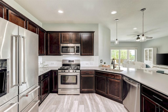 kitchen featuring ceiling fan, appliances with stainless steel finishes, a sink, light countertops, and open floor plan