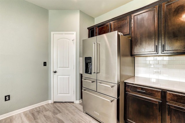 kitchen with dark brown cabinets, light wood-style floors, high end refrigerator, baseboards, and backsplash