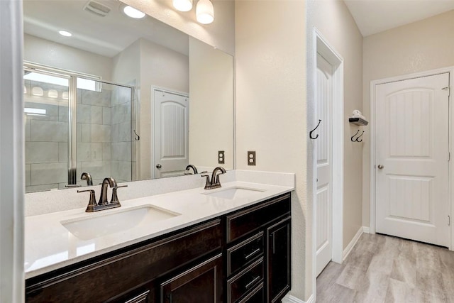 full bath with a sink, a shower stall, double vanity, and visible vents